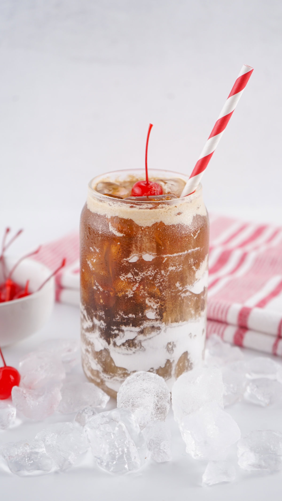 Glass full of ice, coke, and marshmallow fluff, topped with a cherry.