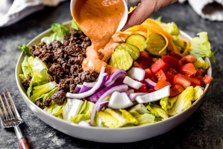 ground venison salad with pickles, tomatoes, and onions with dressing poured on top