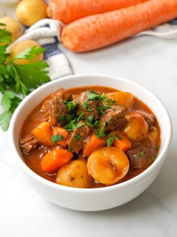 Bowl of instant pot beef stew topped with parsley.