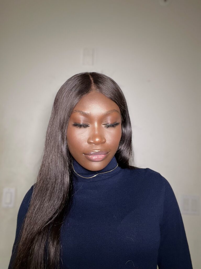 black woman in blue turtle neck and straight hair with soft glam makeup on.