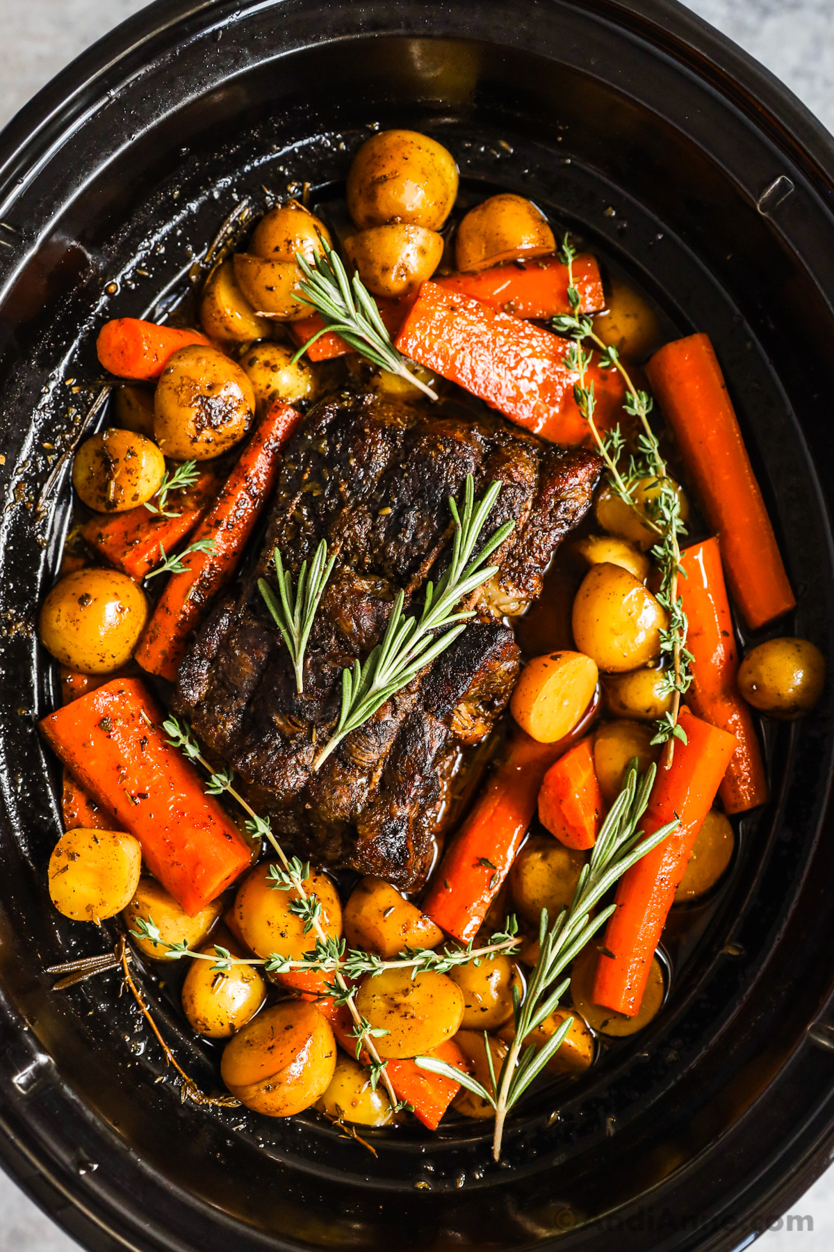 Looking down into a slow cooker with pot roast, potatoes, and carrots.