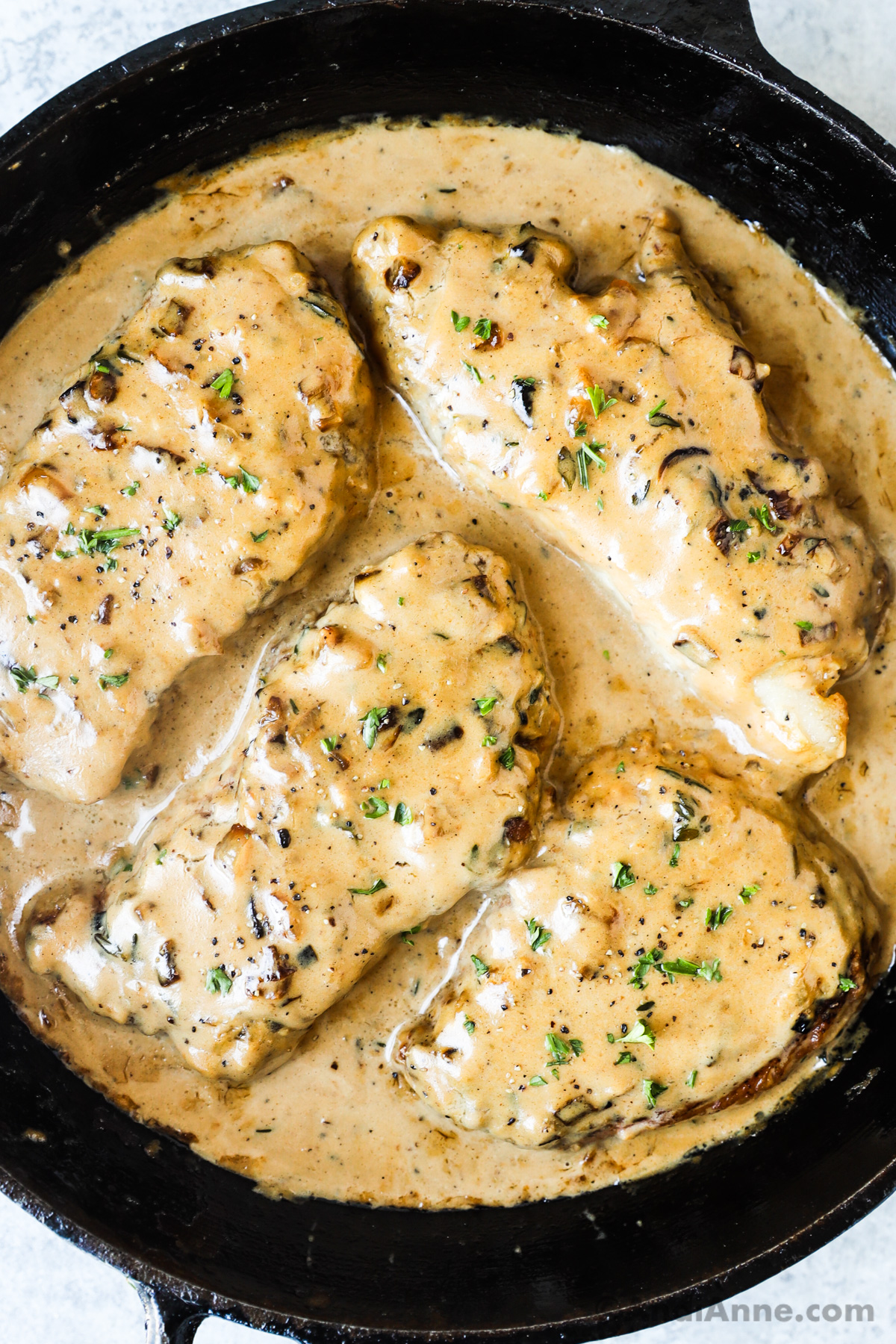 A pan with smothered pork chops in gravy sauce