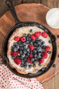 Berry puff in a black pan on wooden board.