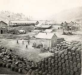 Worker organize 42-gallon oil barrels for loading and shipping.