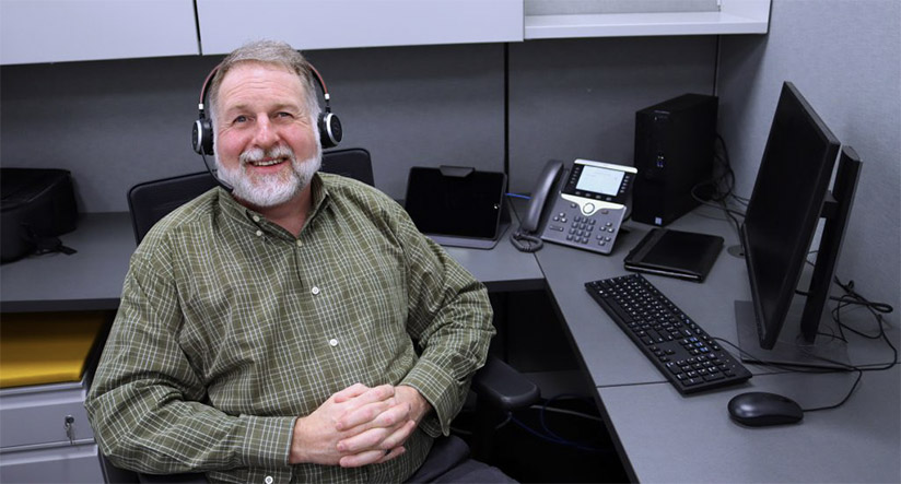 Man sitting at desk wearing headphones looking at camera