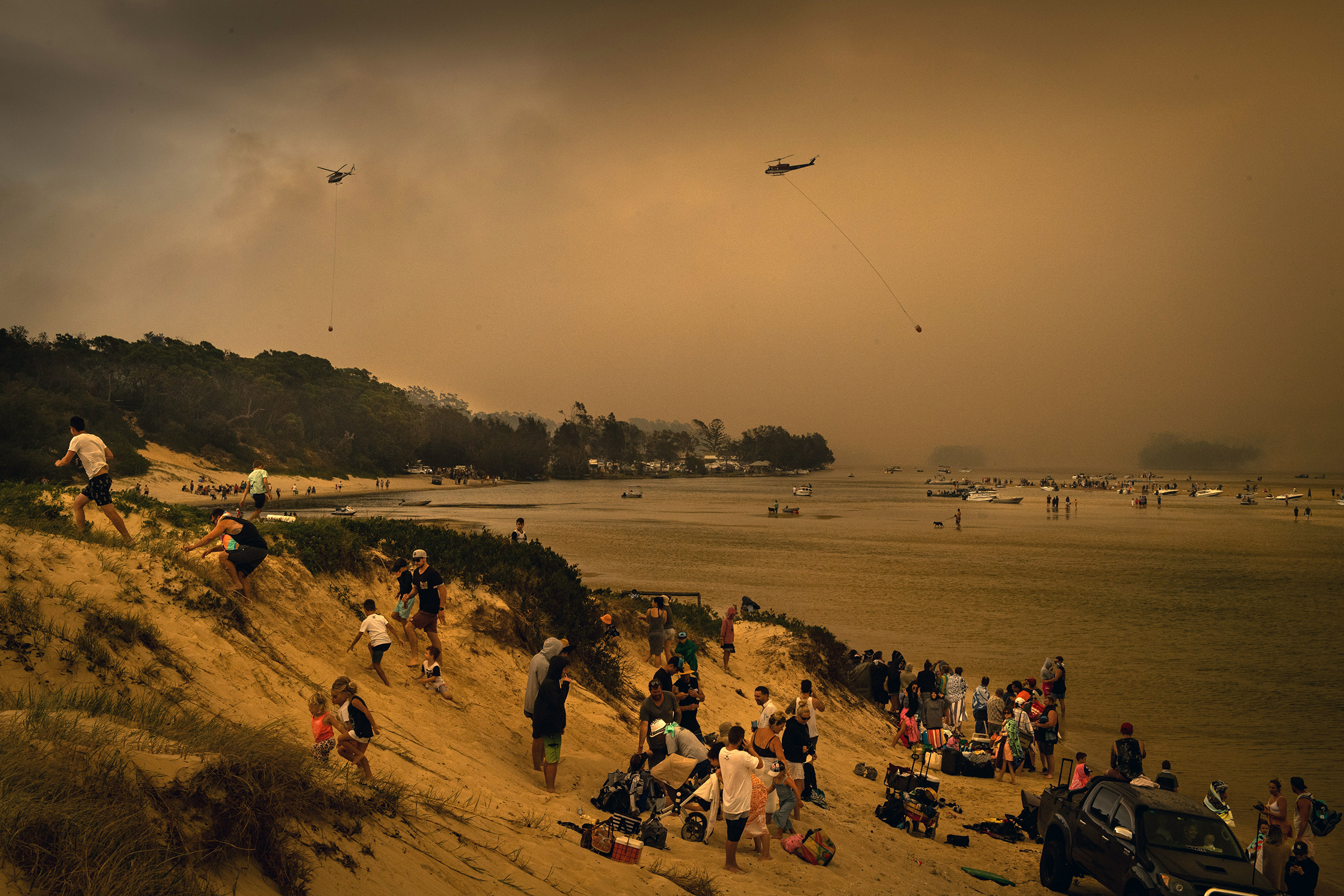 Tourists in Lake Conjola, a popular holiday destination in Australia, take refuge from wildfires on a beach from wildfires on Dec. 31, 2019. (Matthew Abbott—The New York Times/Redux)