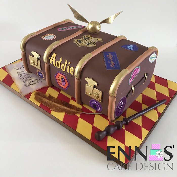 cake in the shape of a trunk, covered with brown fondant, happee birthdae, golden snitch on top, wand on the side