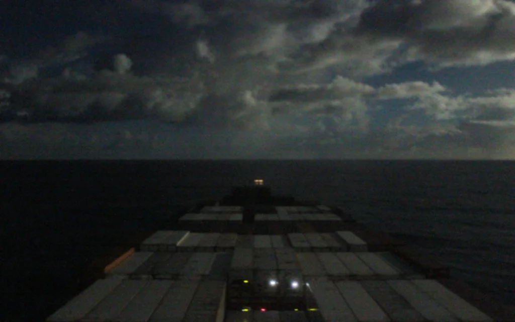 Traveling on a cargo ship across the Pacific Ocean during the night.