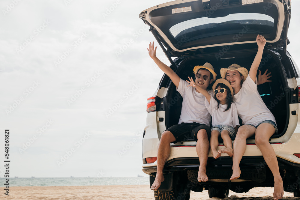 Happy Family Day. Dad, mom and daughter enjoying road trip sit on back car and raise hand up, Family traveling in holiday at sea beach, people having fun in summer vacation on beach with automobile