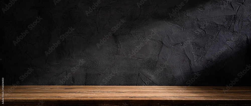 Wooden table or counter top with black stone wall background