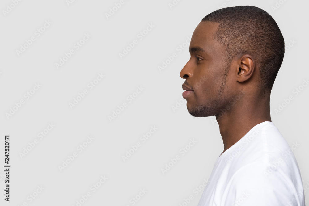 Millennial african american man standing in profile isolated on blank white grey studio background, confident black guy looking forward at copy space thinking of future leadership, side view portrait