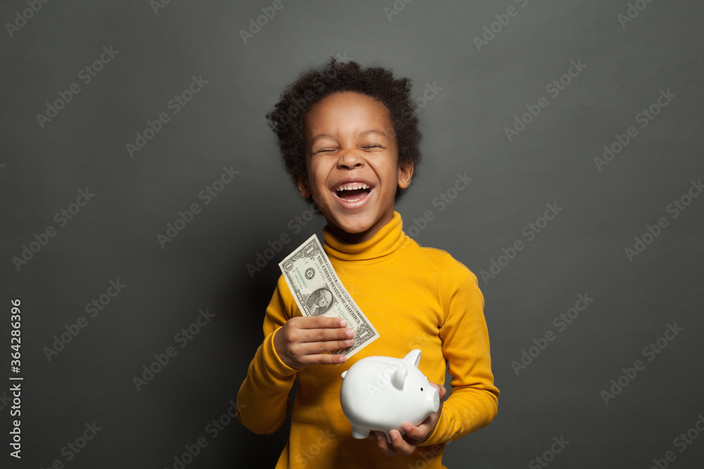 Smart happy black child boy putting in piggy bank one dollars banknote