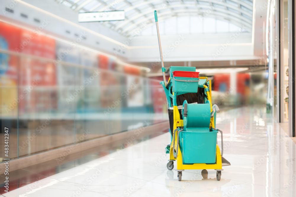 Cleaner cart in a public place. Mobile cart with cleaning products: mop, buckets for cleaning the floor, broom. Ensuring cleanliness and disinfection