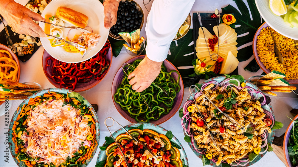 Vertical view of people firends hands taking food from catering table  during party celebration - catering and restaurant concept with mixed chef  food on a table -coloured background and together Stock Photo |