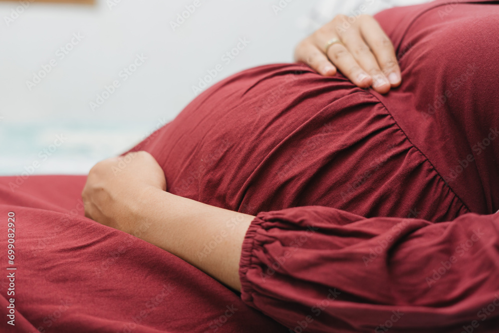 Foto de Muslim pregnant woman holding her belly stomach while lying ...