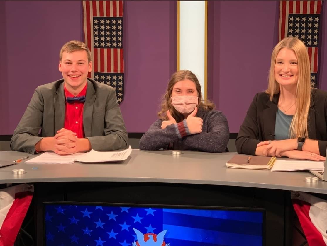 JDM alumni sit at the Center for the Arts Studio news desk during AUTV productions.