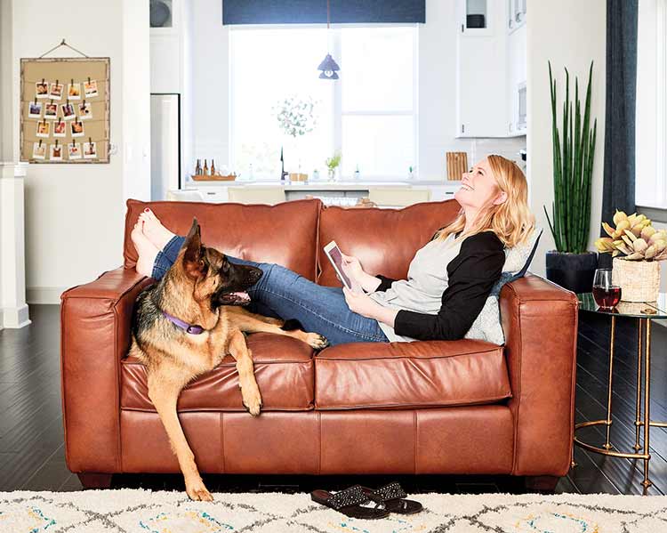 woman and dog reclining on leather couch