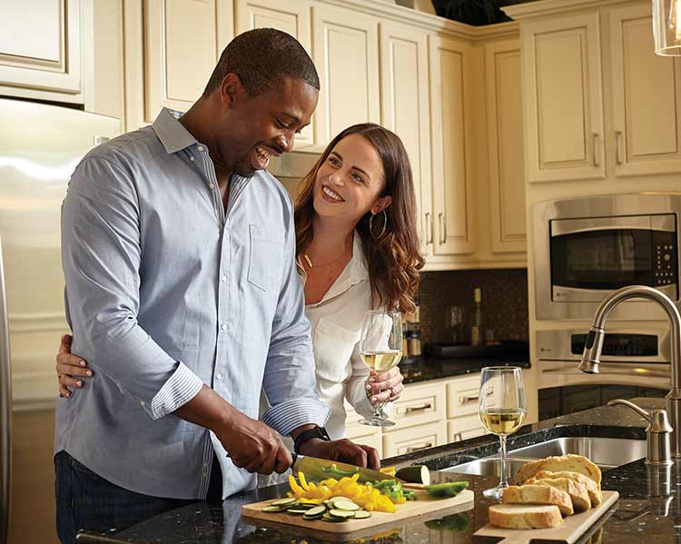 man and woman in kitchen with bread and chopped vegetables