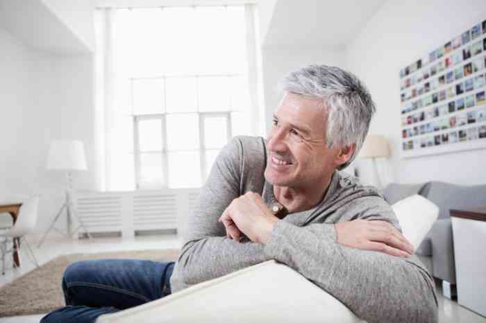 an elderly man smiling on a sofa in his living room