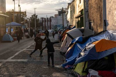 Two boys running around and playing outside of tents in Ciudad Juarez, Mexico.