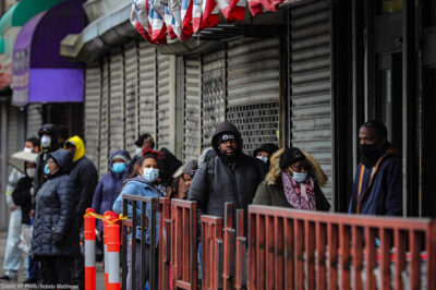 Customers in masks line up outside a grocery store in Brooklyn, NY, waiting to enter after other shoppers have left, because of social distancing efforts during the coronavirus outbreak.