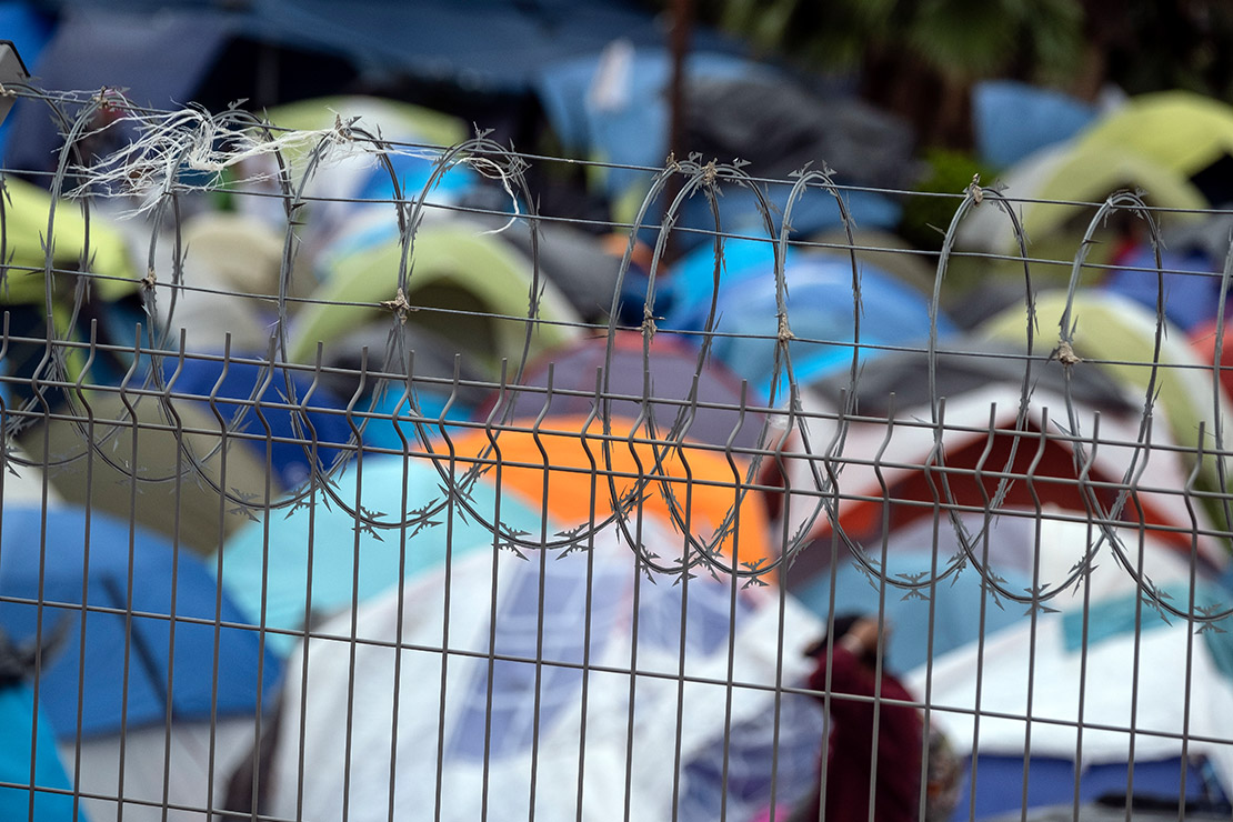 A group of tents with barbed wire in the foreground.