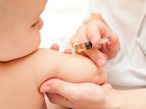 Health care professional giving vaccination shot to young baby