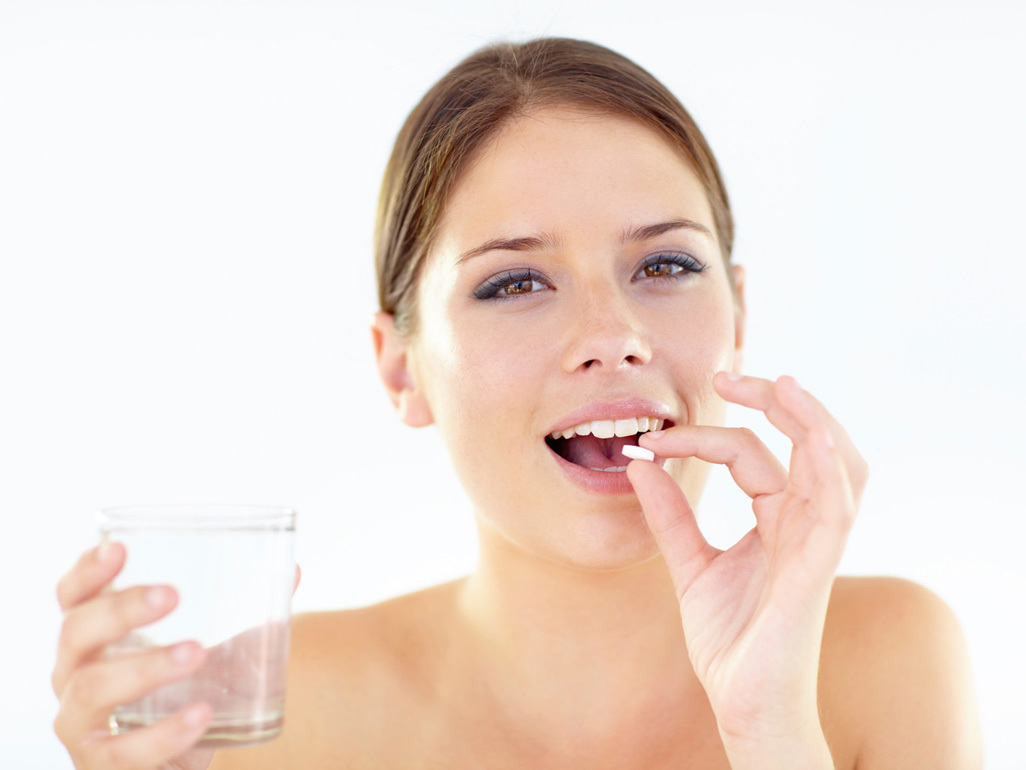 woman taking a tablet with a glass of water