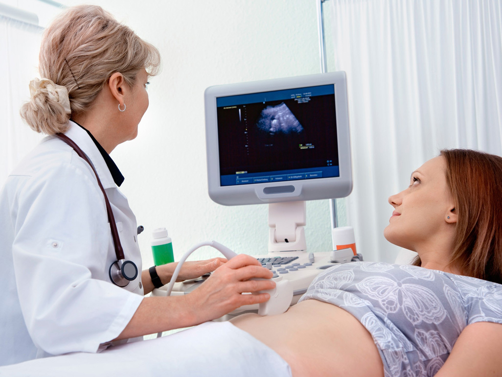 Doctor performing ultrasound on pregnant woman