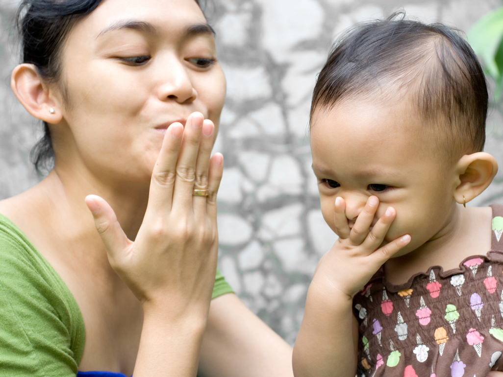 mom and girl kissing their palms