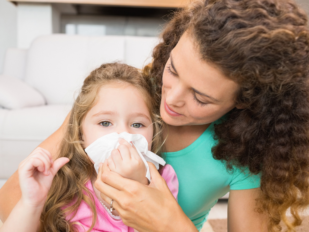 mom helping daughter blow nose