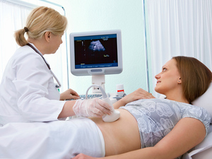 Woman having dating scan looking at ultrasound image of baby on a screen