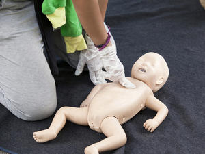 adult performing cpr on a baby doll