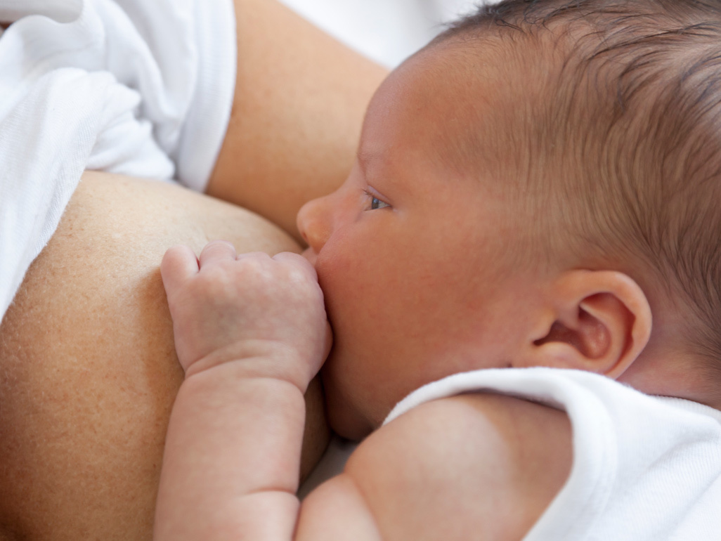 Newborn baby feeding from very full breast