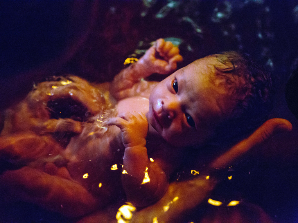 Newborn baby being held in the birthing pool