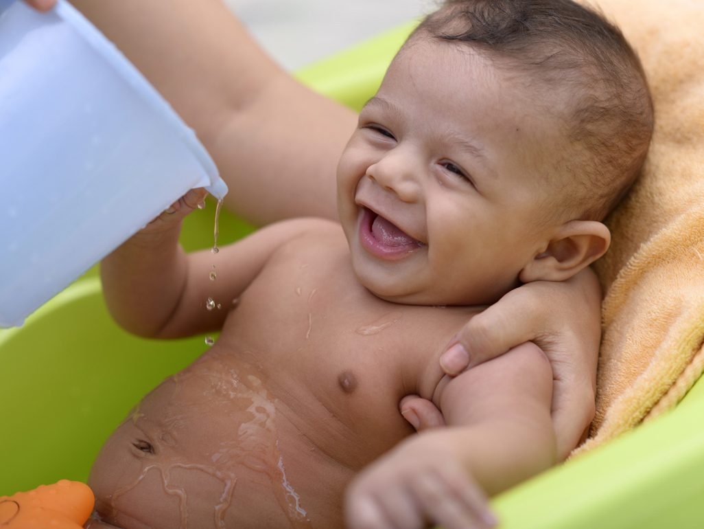 small baby smiling while getting a bath