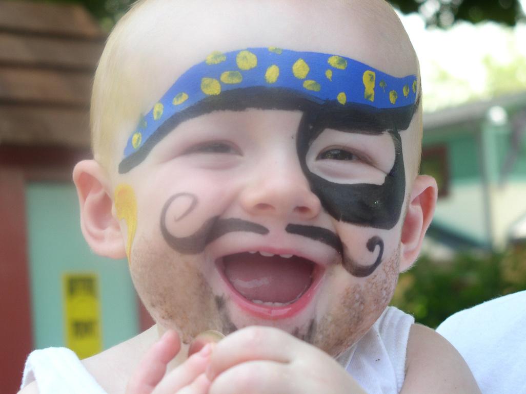 very happy child with drawn pirate mask on his face