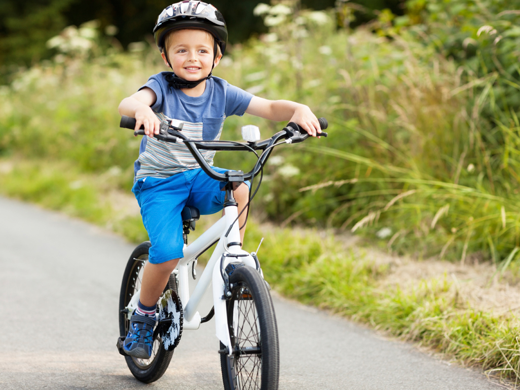 child riding a bicycle with a helmet on his head