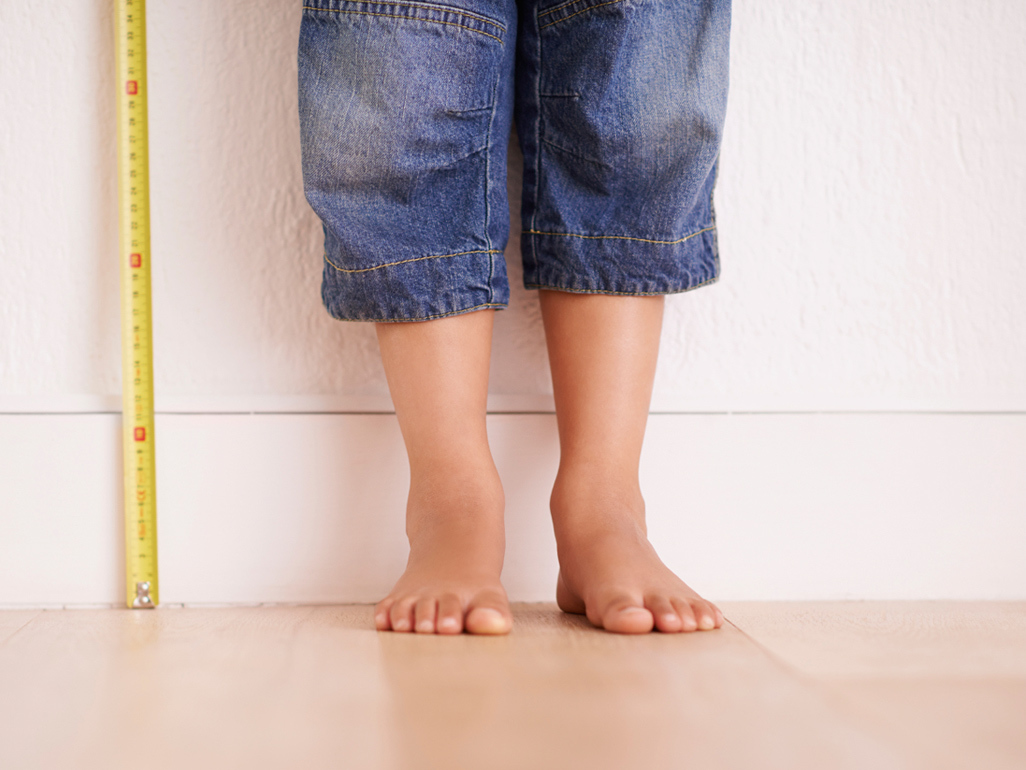 child's feet next to a measuring tape