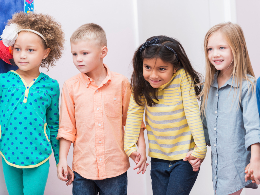 five children standing next to each other, holding their hands