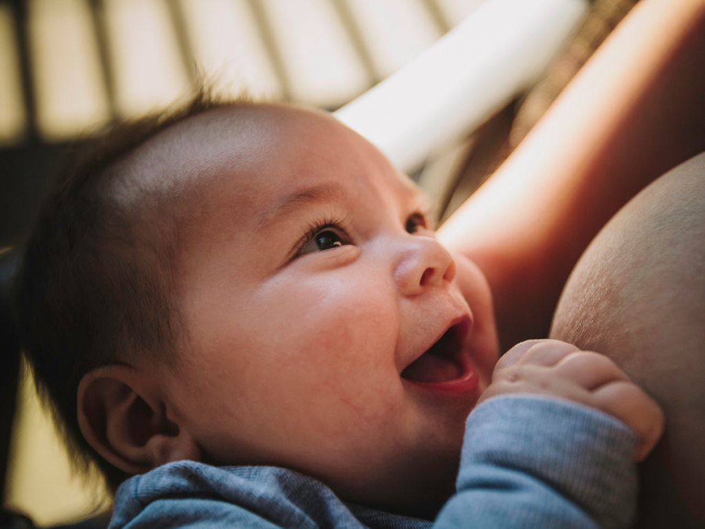 Baby smiling up at mom during a break from nursing