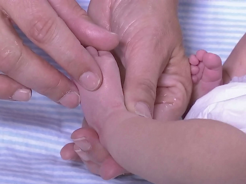 adult hands touching a newborn's baby's foot