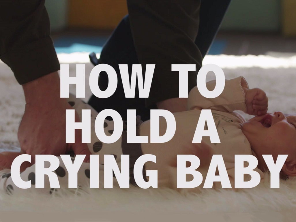 baby on ground with text: How to hold a crying baby