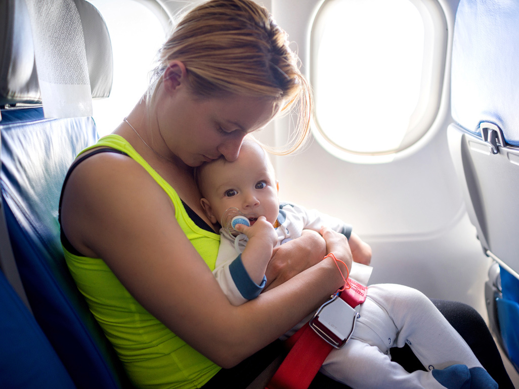 mother holding baby on lap inside airplane