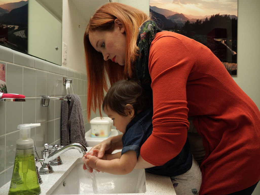 child and mom scrubbing hands in sink