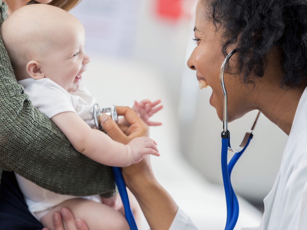 smiling doctor examining 4-month-old baby