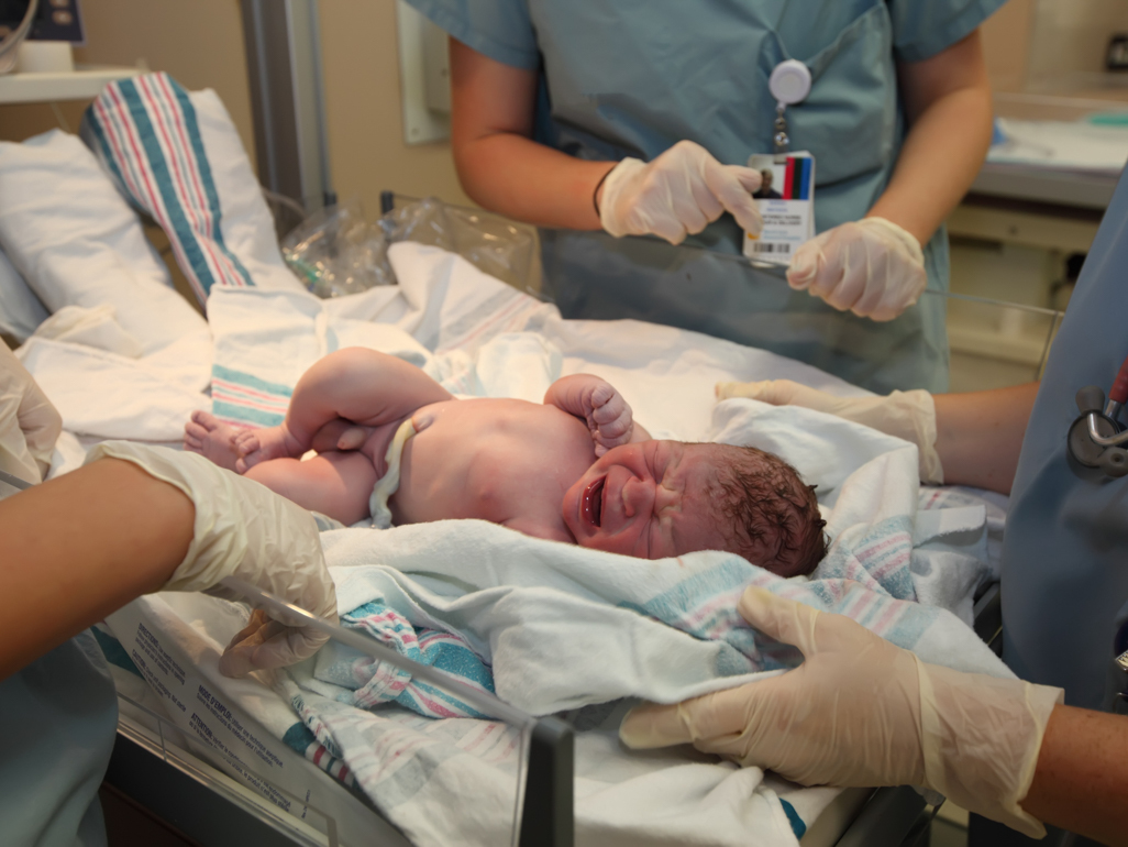 newborn crying in hospital surrounded by doctors