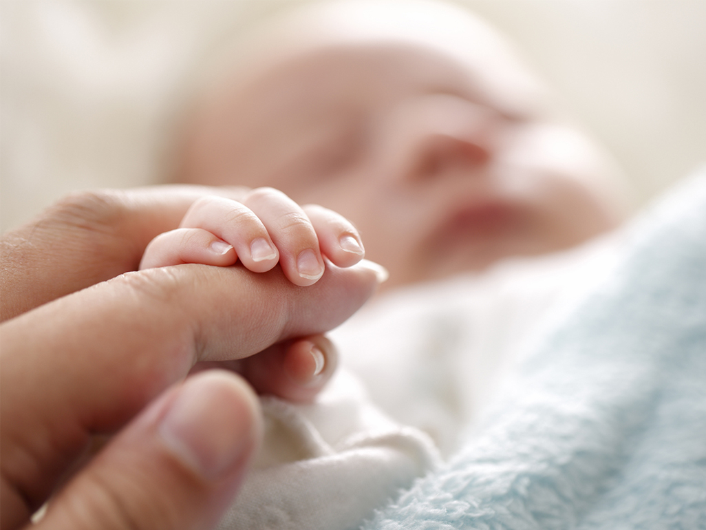 baby holding mother's finger with her tiny hand