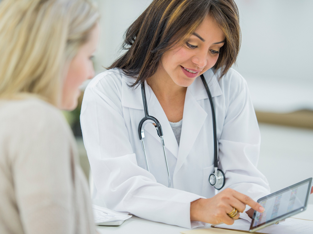 Doctor showing pregnant woman information on a tablet computer