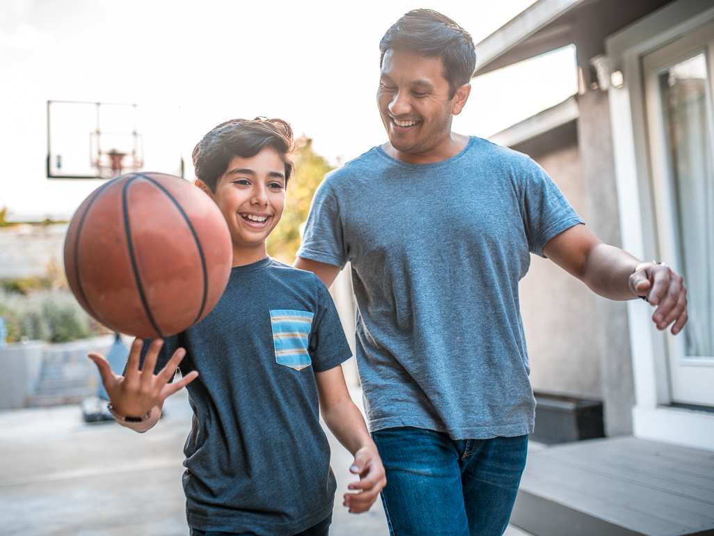 young boy playing basketball with his dad